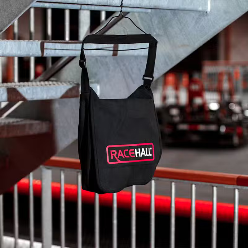 En sort taske med RaceHall logo hængende på en metallisk struktur.